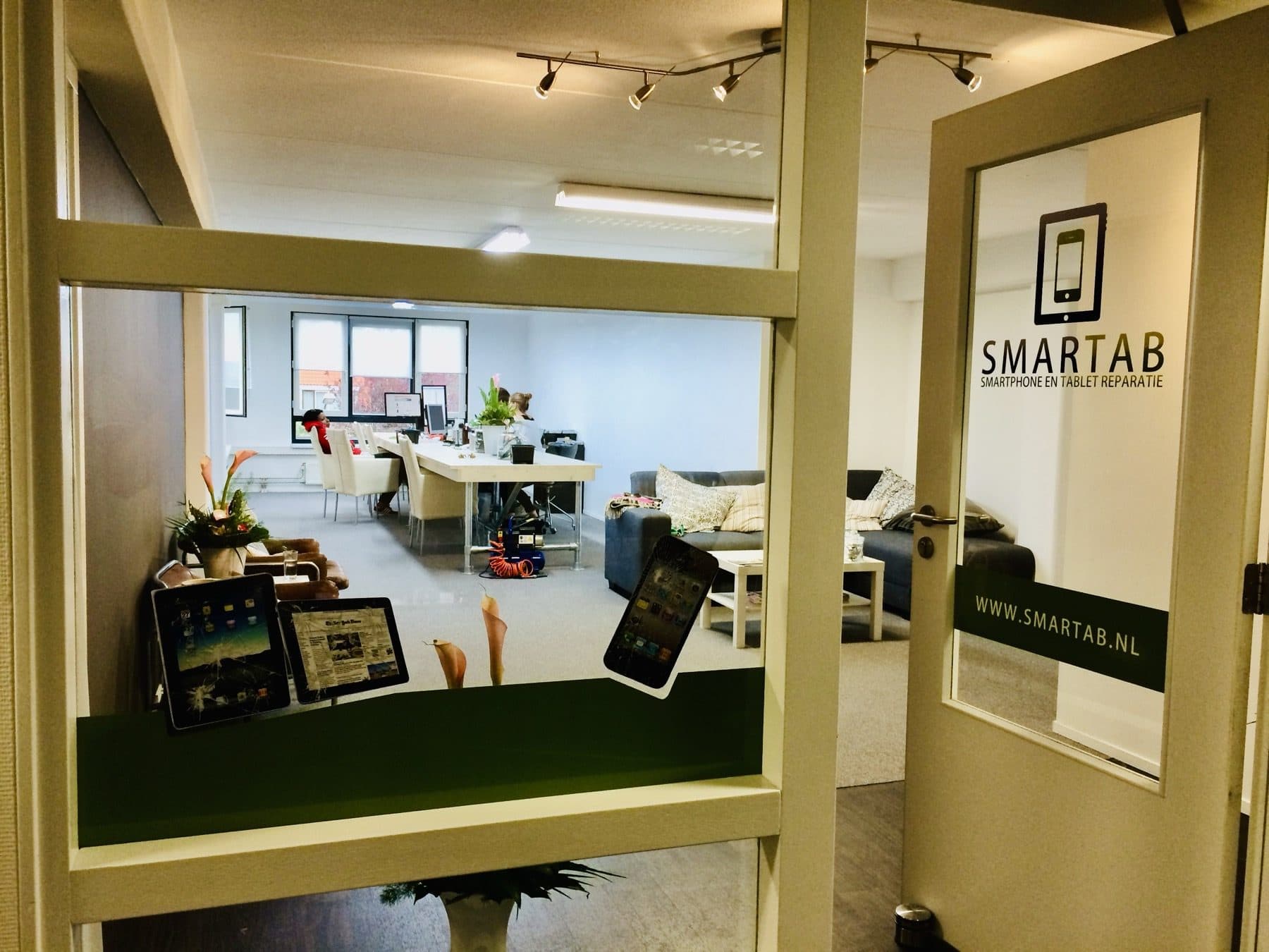 De eerste SMARTAB-winkel: de glazen deur met het oude logo en zicht op het kantoor erachter
